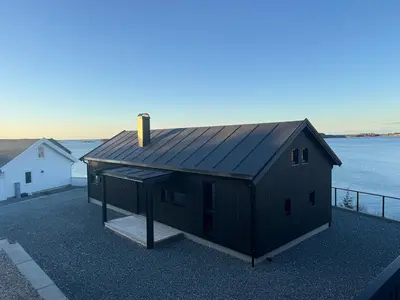 a small black house on the side of a body of water at Sunset Island Retreat, Brand New Waterfront Cabin in Herland