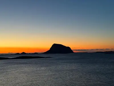 a mountain in the middle of the ocean at sunset at Sunset Island Retreat, Brand New Waterfront Cabin in Herland