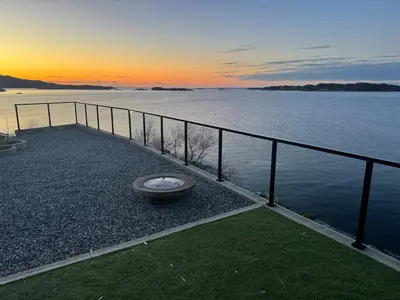 a dog bowl sitting on the gravel next to the water at Sunset Island Retreat, Brand New Waterfront Cabin in Herland