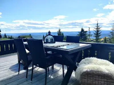 a table and chairs on a deck with a view at Exclusive family cabin in Hafjell ski-in-ski-out in Hafjell