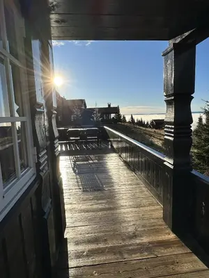 a wooden porch of a house with the sun shining at Exclusive family cabin in Hafjell ski-in-ski-out in Hafjell