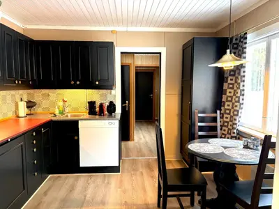 a kitchen with black cabinets and a table and a dining room at Magic Cabin by Lake & Forest , Peace, Views & Outdoor Fun, in Opphus