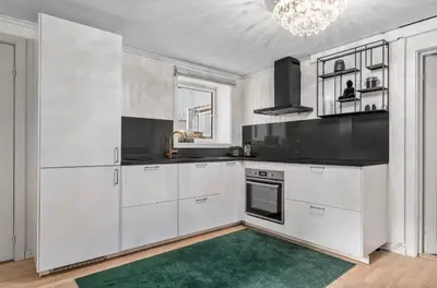 a kitchen with white cabinets and a green rug at Spacious 3 Bedroom Basement Apartment with Parking, Close to Trondheim City Center in Trondheim