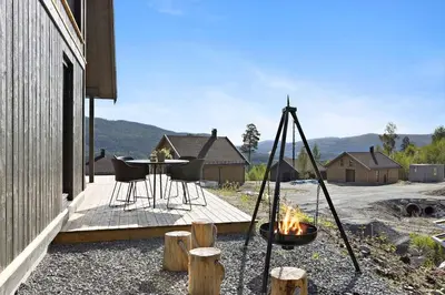 a patio with a table and chairs and a fire pit at New and great cabin at the foot of Norefjell in Noresund
