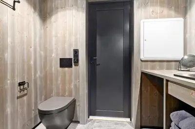 a bathroom with a toilet and a black door at New and great cabin at the foot of Norefjell in Noresund