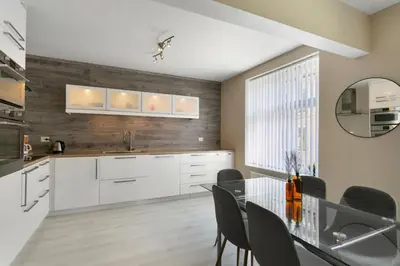 a kitchen with white cabinets and a glass table at Centrum apartment 2 in Ålesund