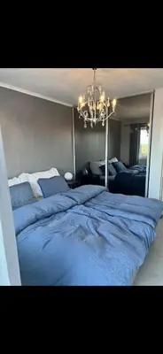 a bedroom with a large blue bed with a chandelier at Koselig bolig med stor stue, 10 min from Solsiden! in Trondheim