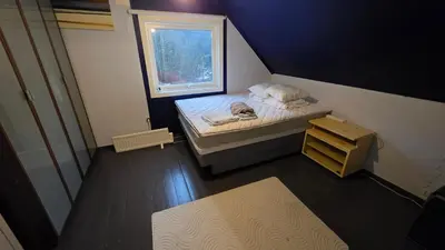 a small bedroom with a bed and a window at Bedroom with private living room in Bergen