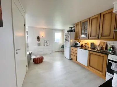 a kitchen with wooden cabinets and a white refrigerator at Solbakken, nice Apartment by the Sea in Ålesund in Ålesund