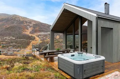 a house with a hot tub on a deck at Skarhaug Panorama Lodge in Stranda