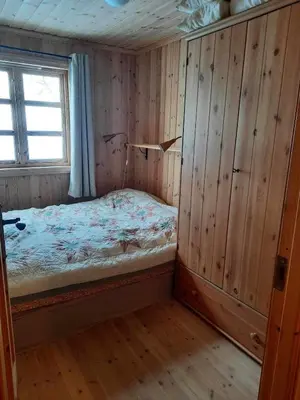a bedroom with a bed in a wooden room at Familiehytte på Botn, Vågslid til leie in Botn