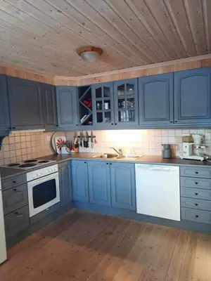 a kitchen with blue cabinets and a wooden ceiling at Familiehytte på Botn, Vågslid til leie in Botn