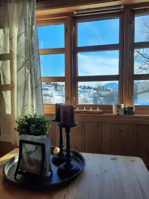 a table with a candle in front of a window at Familiehytte på Botn, Vågslid til leie in Botn