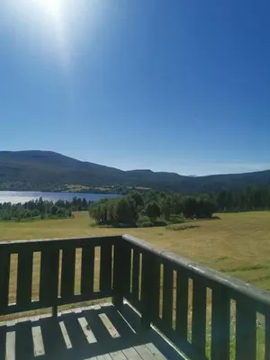 a deck with a view of a field and a lake at Åsrud seter i Jotunheimen in Randsverk