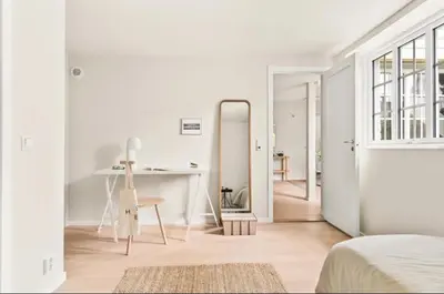 a white room with a bed and a table and a mirror at Lev livet i Bergen - Stor moderne leilighet in Bergen