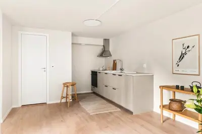 a kitchen with white walls and a wooden floor at Lev livet i Bergen - Stor moderne leilighet in Bergen