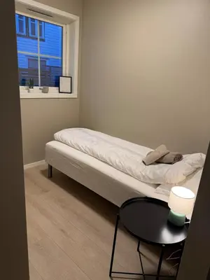 a bedroom with a bed with a table and a window at Sandvik's stuen in Bergen