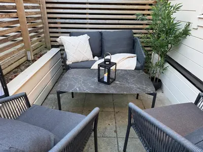 a patio with a couch and a table and two chairs at Sandvik's stuen in Bergen