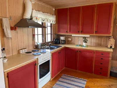 a kitchen with red cabinets and a stove top oven at Nedre Flaata Seter in Nørdstebø