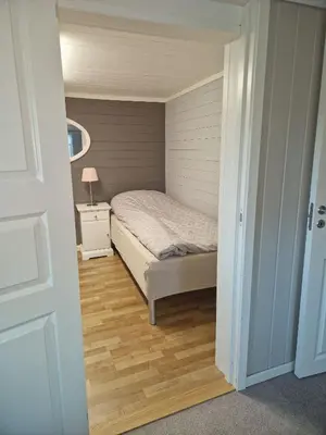 a small bedroom with a bed and a night stand at Cosy living room, bedroom and bathroom and kitchen area in Kolavåg