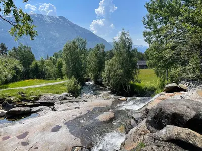 a river with rocks and trees and a mountain at The house by the waterfall in Breim