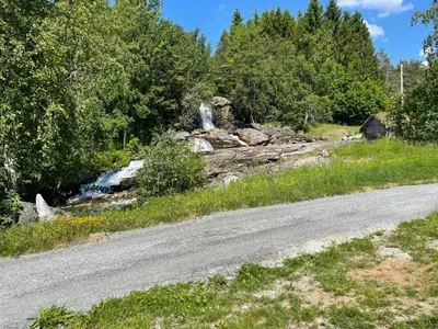 a road next to a river with a waterfall at The house by the waterfall in Breim