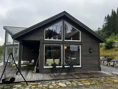 a small house with a table and chairs on a deck at Lunvik - Flott hytte ved Nysætervatnet in Sykkylven