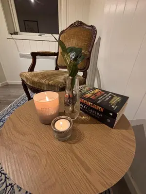 a table with a candle and books and a chair at Moderne leilighet med 2 soverom for jobb og ferie in Raufoss