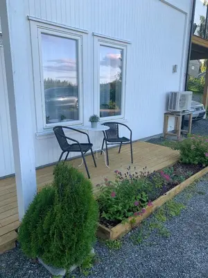 a patio with two chairs and a table and two windows at Moderne leilighet med 2 soverom for jobb og ferie in Raufoss