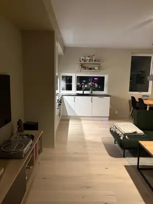 a living room with a couch and a table and a kitchen at New modern apartment, close to airport in Bergen