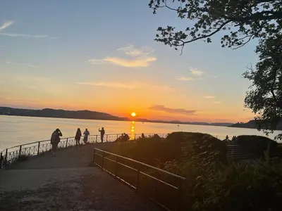 a group of people walking on a pier at sunset at Corner apartment with balcony in Bergen in Bergen