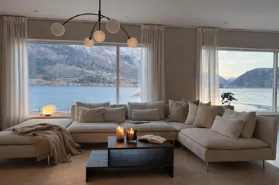 a living room with a large couch and a large window at Private house on cider farm - fjord, beach & jetty in Sogndal