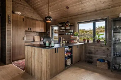 a kitchen with wooden walls and a large island in a room at Lykka - lovely cabin with amazing view in Torpo