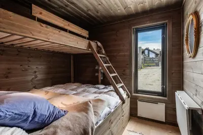 a bunk bed in a wooden room with a ladder at Lykka - lovely cabin with amazing view in Torpo