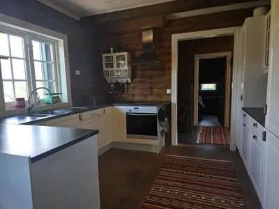 a kitchen with white appliances and a wooden wall at Kilodden, Lakeside Mountain Cabin with Stunning Views in Tuddal
