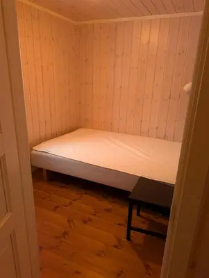 a small bed in a small room with a wooden floor at Håvi Solsiden 11C in Trysil