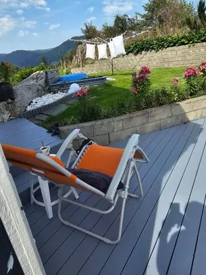 a lounge chair on the deck of a house at Charming and cozy house in Vindafjord in Dørheim