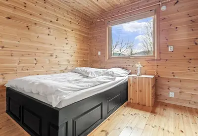 a large bed in a wooden room with a window at Look at this view! 3 BR house overlooking Hardangerfjorden in Kvam