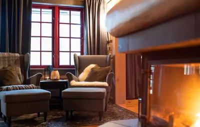 a living room with a fireplace and chairs and windows at 2 Bedroom Gorgeous Apartment In Bjorli in Bjorli