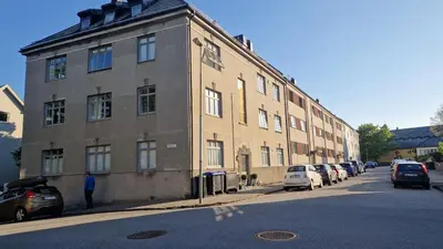 a large brick building with cars parked in front of it at Topp floor apartment with one bedroom & a loft in Ålesund