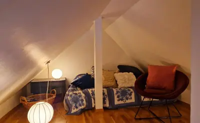 a room with a bed and a chair in a attic at Topp floor apartment with one bedroom & a loft in Ålesund