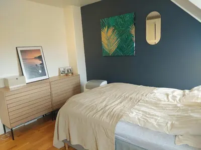 a bedroom with a bed and a dresser and a painting at Topp floor apartment with one bedroom & a loft in Ålesund