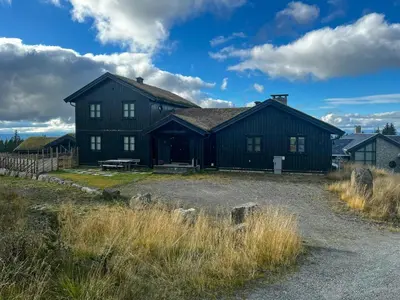 a large black house with a bench in front of it at Family Cabin With Views Of Jotunheimen in Øyer