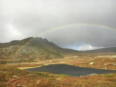 a rainbow over a field with a lake and a mountain at Family-Built Cabin At The Three Line in Eggedal