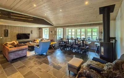 a living room with a fireplace and a dining room at Cosy Cabin With Jacuzzi Right By The Ski Slope in Norheimsund