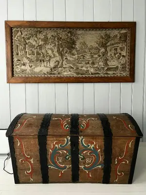a wooden trunk sitting on a table in front of a painting at Historic Timber House From The 1800S In Nordfjord in Olden