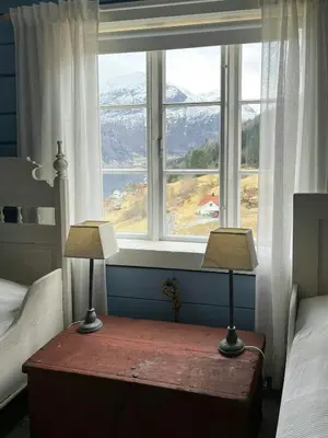 two lamps on a table in front of a window at Historic Timber House From The 1800S In Nordfjord in Olden