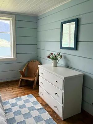 a bedroom with a dresser and a blue wall at Historic Timber House From The 1800S In Nordfjord in Olden