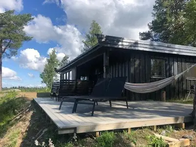 a hammock on a deck in front of a cabin at Handmade Cabin By Pond On Golsfjellet in Gol
