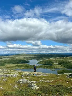 a man standing on top of a hill overlooking a lake at Unique Cabin And Freestanding Sauna With Views in Aurdal